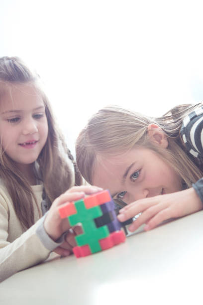 istock Two Cheerful Schoolgirls Having Fun with Puzzle Toy 1263966128