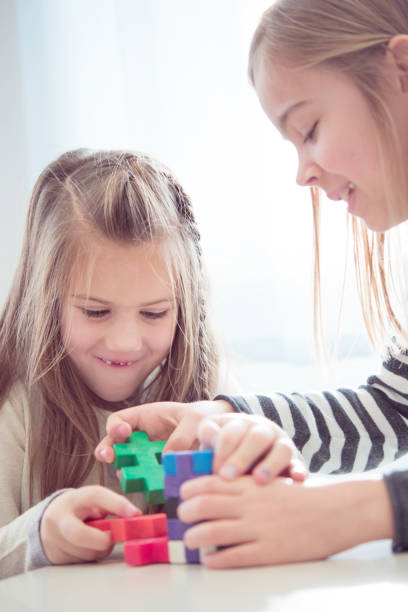 istock Schoolgirls on a Break Playing with Block Puzzle 1263966142