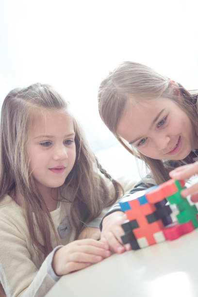 istock Two Cheerful Schoolgirls Having Fun with Puzzle Toy 1263966151
