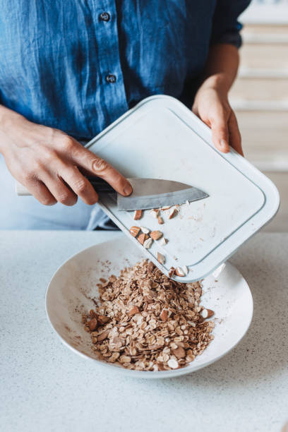 istock Hands of an Anonymous Woman Adding Almonds into a Bowl With Roled Oats 1263968041