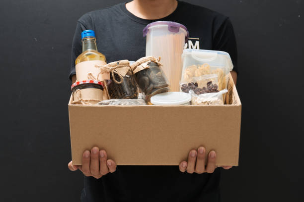 istock A man holding a donation box of different products on dark background 1263989283