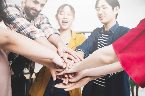 istock Co-working startup business team and teamwork concept. Young team putting hands up in creative office. Happy and cheerful people giving strength motivation 1263993505