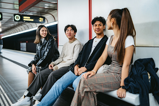 Group of Asian teenagers waiting for a ride in subway station and talking.