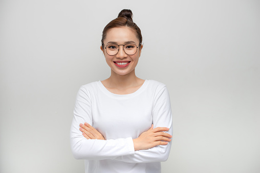 Young woman standing over isolated white background happy face smiling with crossed arms looking at the camera.