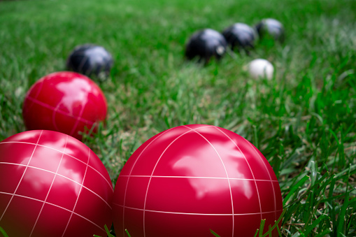 Red and dark blue bocci balls on a green grass lawn playing the game