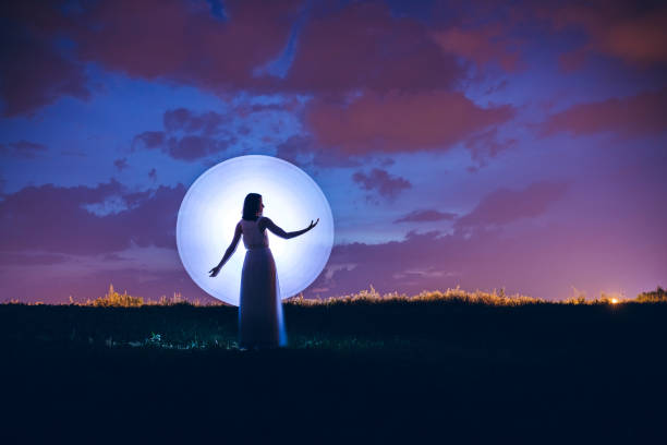 Young woman silhouette and moon. Light painting.