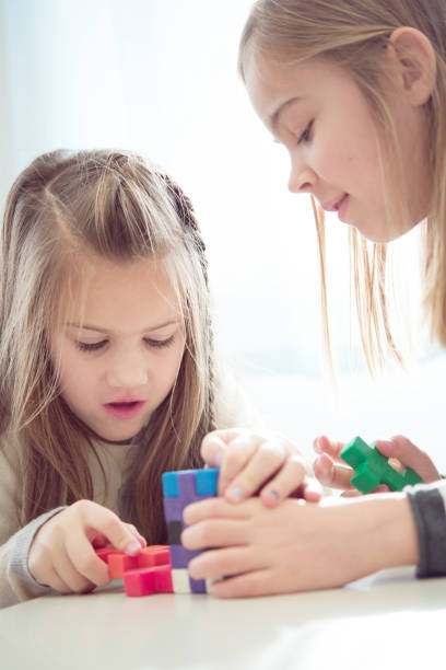 istock Schoolgirls on a Break Playing with Block Puzzle 1264008306
