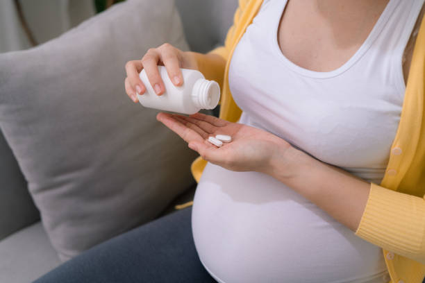 istock A pregnant woman sits at home on a light sofa. She's getting ready to take a pill. 1264015277