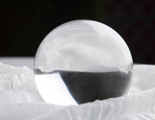 istock Crystal glass ball sphere transparent on white fabric and dark background. 1264015578