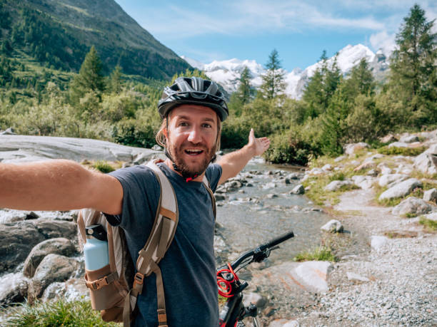 istock Young man mountain biker on trail takes selfie 1264025684