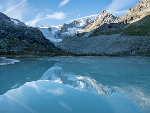 Spectacular view of Moiry glacier at sunrise, sunlight shining on mountain peaks. Reflection on blue lake