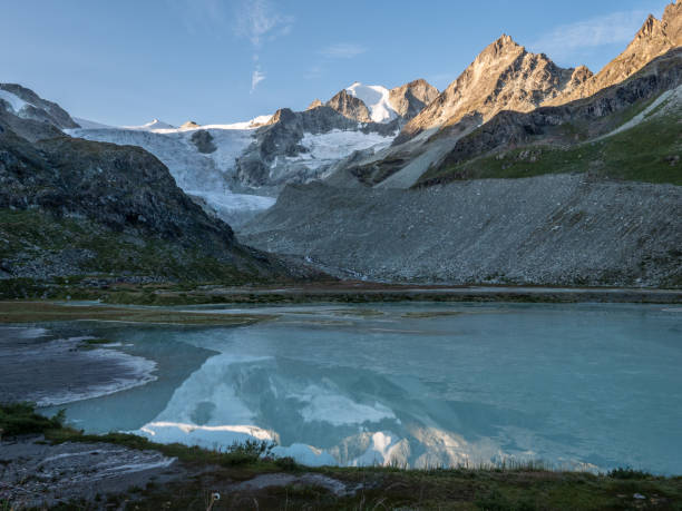 Spectacular view of Moiry glacier at sunrise, sunlight shining on mountain peaks. Reflection on blue lake