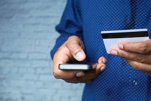 istock Man hand holding credit card and using smart phone shopping online 1264037658