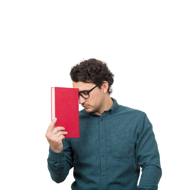 istock Tired student guy looking down with pessimistic emotion, holding a book, isolated on white background. Confused young man has learning troubles, problems on studying process, education concept. 1264037665