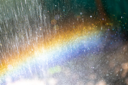 Abstraction, blurred rainbow in water drops. Natural background or texture. splashing water in the sun creates a rainbow color.