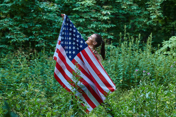 istock attractive girl posing with american flag in forest park 1264044759