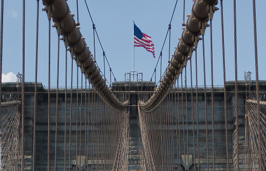 American flag on top of brooklyn bridge and details of the bridge architecture