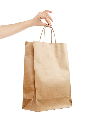 Female hand holding kraft paper shopping bag. Design mockup Isolated on white background.