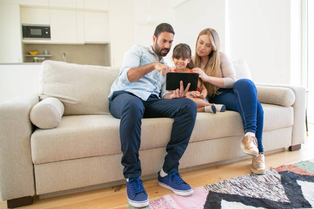 istock Happy family sitting on couch, using online app on tablet 1264051582