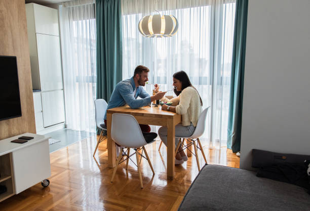 istock Young couple eating salad while sitting at a table at home. 1264051829