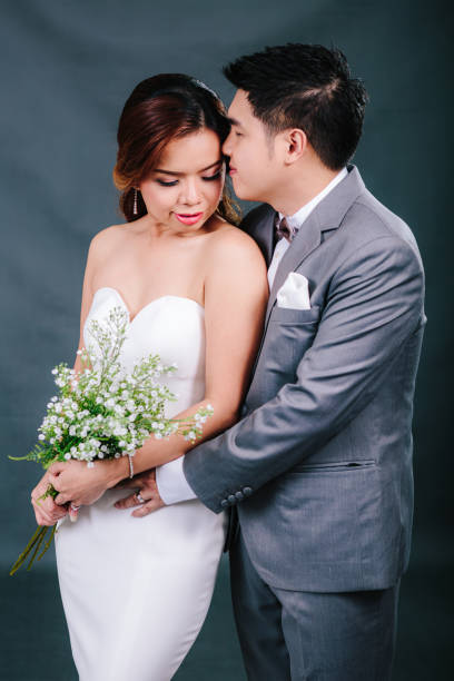 istock Young asian groom and bride posing and smiling in studio for pre-wedding shot 1264054857