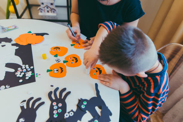 jeune mère avec le fils d’enfant en bas âge faisant des citrouilles d’artisanat pour des vacances d’halloween - spider mum photos et images de collection