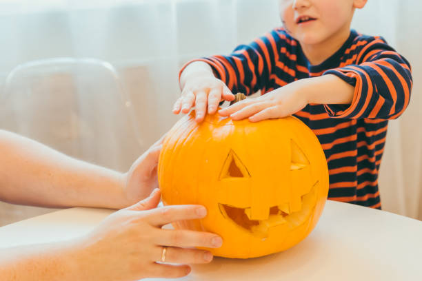 istock little boy makes halloween pumpkin head at home 1264060313