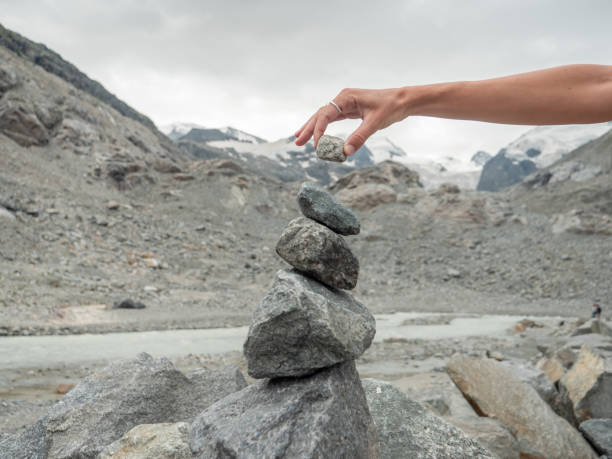 istock View of hand stacking rocks on mountain trail, glacier view 1264062301