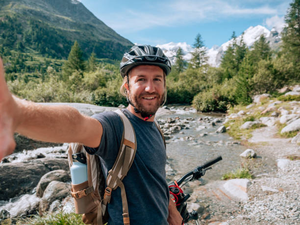 istock Young man mountain biker on trail takes selfie 1264062458