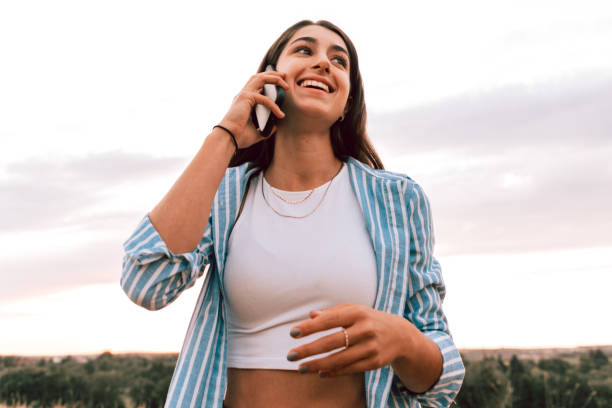 adolescente sorridente che ha una divertente telefonata all'aperto sul telefono cellulare - bassiera foto e immagini stock