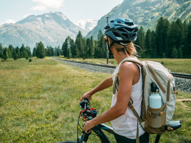 Woman on mountain bike looking at panorama. People enjoying outdoor activities in summer. Girl mountain biker looking at glacier and mountains