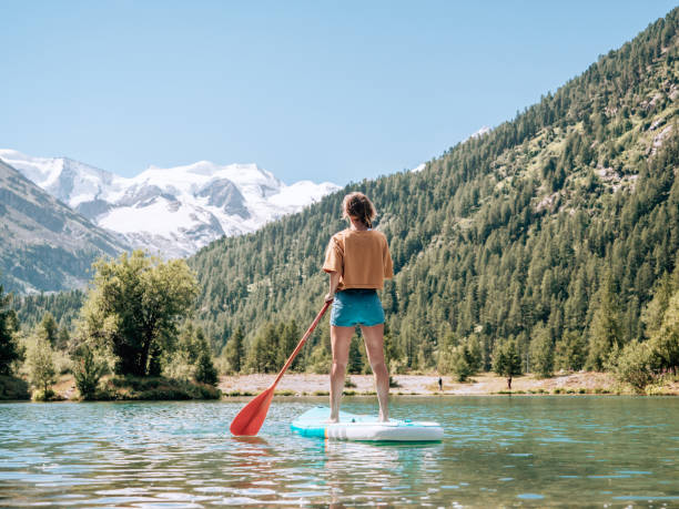 stand up paddle con vista, donna su sup in montagna guardando il ghiacciaio - paddleboard oar women lake foto e immagini stock