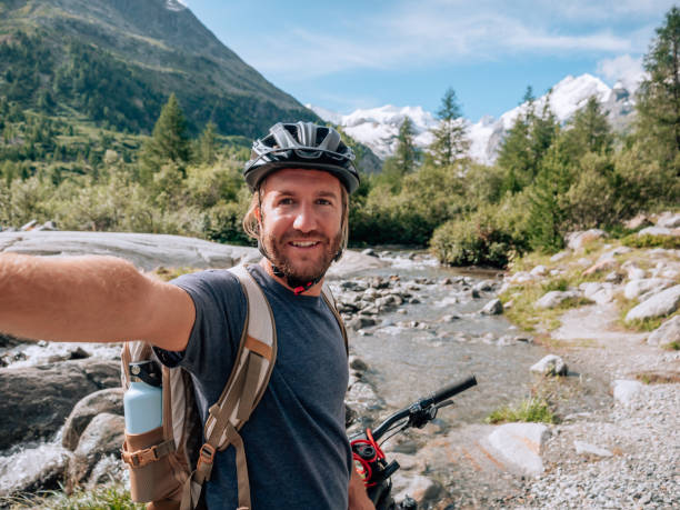 jeune homme vététiste sur la piste prend selfie - engadine european alps switzerland water photos et images de collection