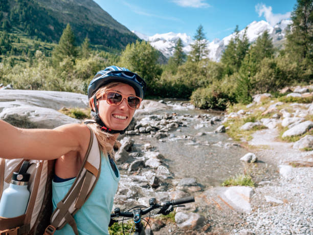 istock Young woman mountain biker on trail takes selfie 1264064279
