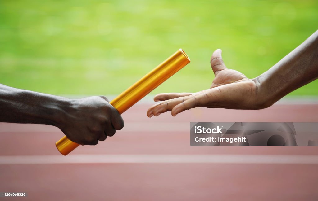 Two men passing golden baton in stadium Relay Baton Stock Photo
