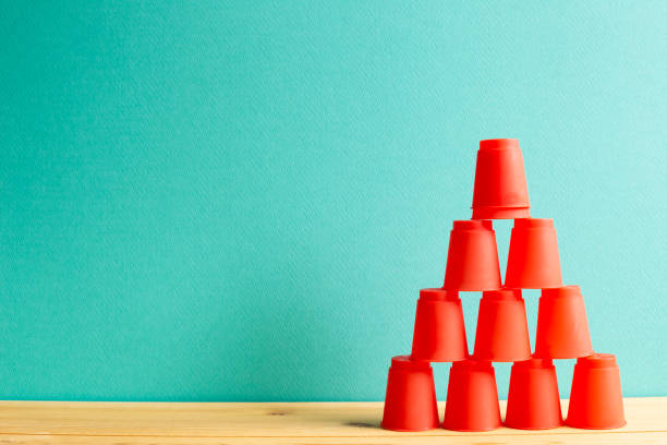 Pyramid of red plastic cups on wooden table with green background