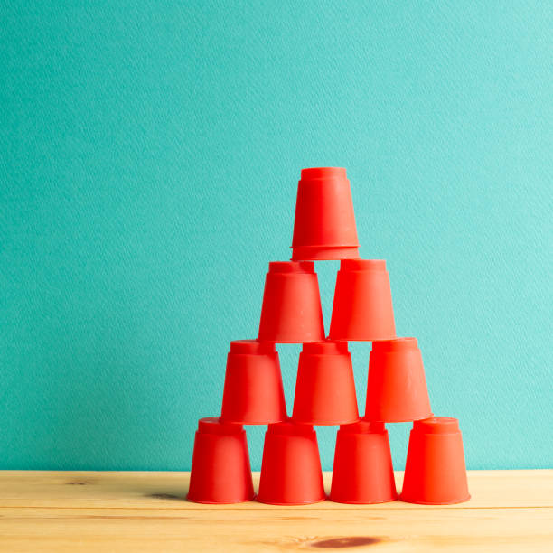istock Pyramid of red plastic cups on wooden table with green background 1264070472