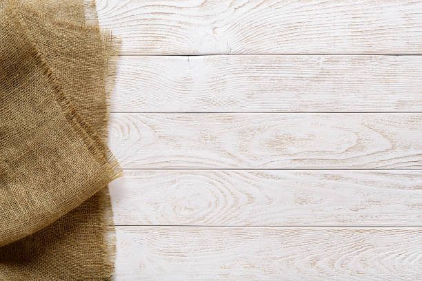 istock Copy space on a rustic textured wood tabletop painted with white paint and burlap of natural color on the side. Empty surface of textured wood planks and sackcloth. 1264071908
