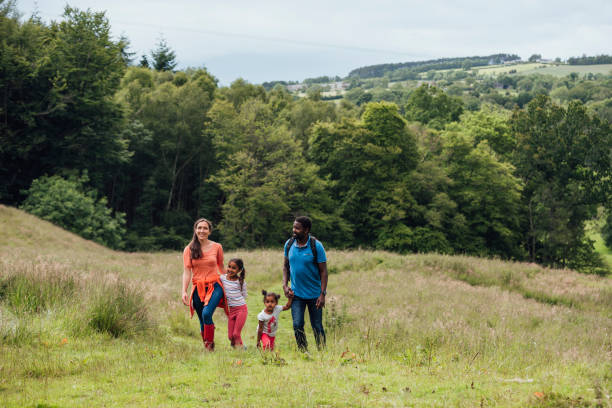 Family Day Out Happy family walking up through the grassy hills in Northumberland. wide shot stock pictures, royalty-free photos & images