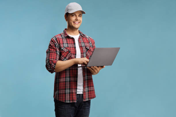 istock Young man in a shirt holding a laptop computer and looking at the camera 1264073867
