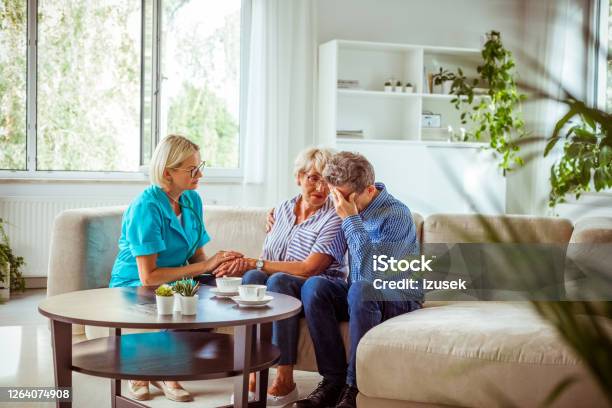 Nurse Consoling Worried Senior Couple Stock Photo - Download Image Now - Crying, Nurse, Senior Men