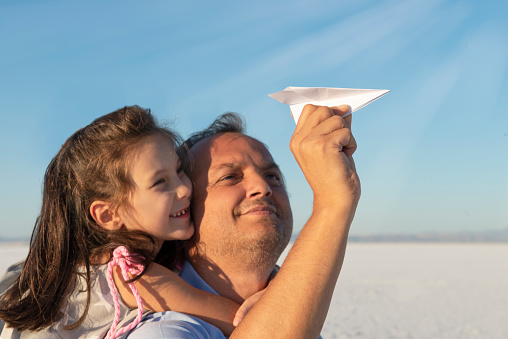 Father playing paper aeroplanes with his daughter.
