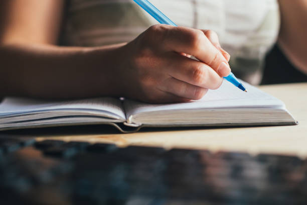 istock woman writing pen in notebook, phone, keyboard 1264075295