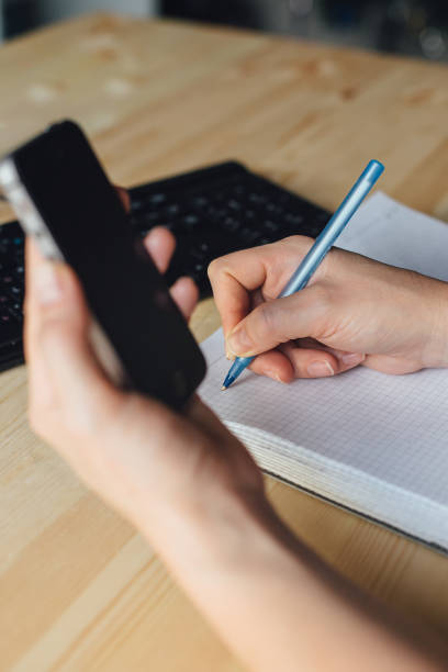 istock woman writing pen in notebook, phone, keyboard 1264075315