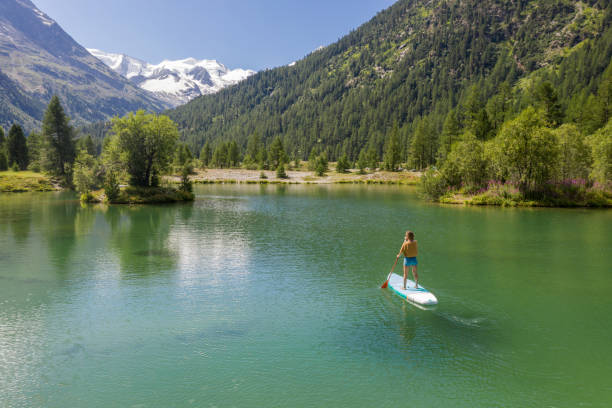 drone view of woman on sup in the mountains looking at glacier - european alps switzerland glacier high angle view imagens e fotografias de stock