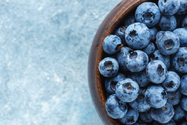 istock Fresh blueberries in wooden bowl top view 1264075688
