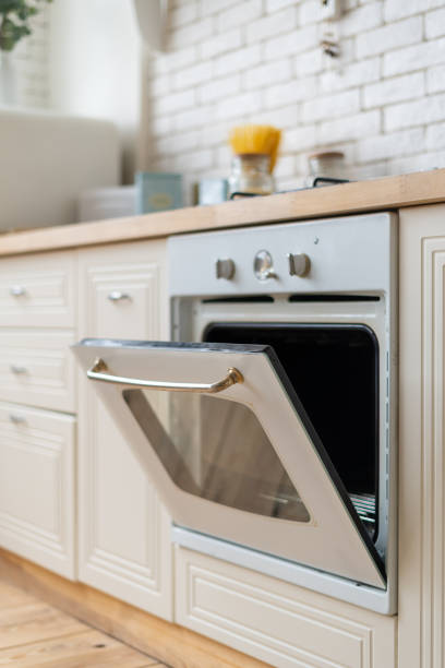 White kitchen in apartment with modern interior Vertical view of modern built in oven equipment with open door. White kitchen in apartment with contemporary interior oven door stock pictures, royalty-free photos & images