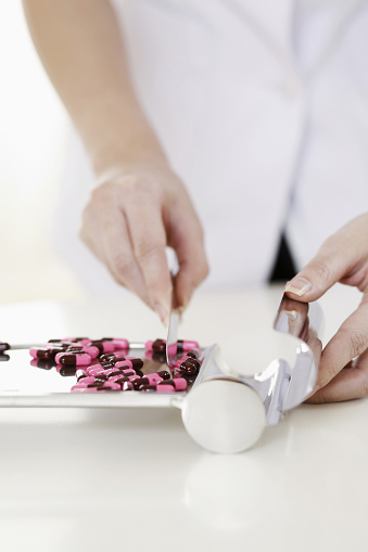 Doctor counting pills on pharmaceutical tray