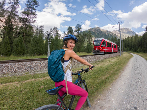 Woman on mountain bike looking at panorama. People enjoying outdoor activities in summer. Girl mountain biker looking at glacier and mountains