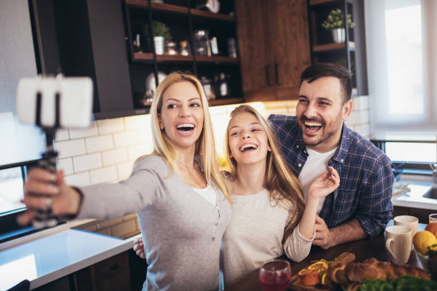istock Cute girl and her beautiful parents are doing selfie using a smart phone and smiling while baking in kitchen at home 1264083294